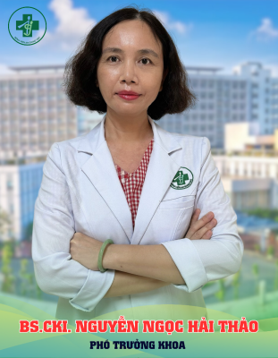 A person in a white coat with her arms crossed Description automatically generated
