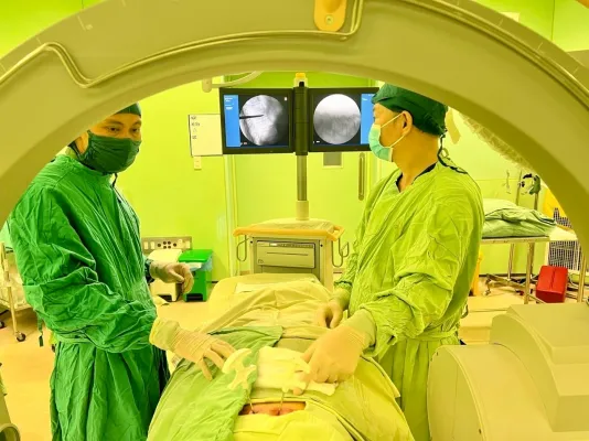 A group of people in green scrubs and masks in a hospital room Description automatically generated